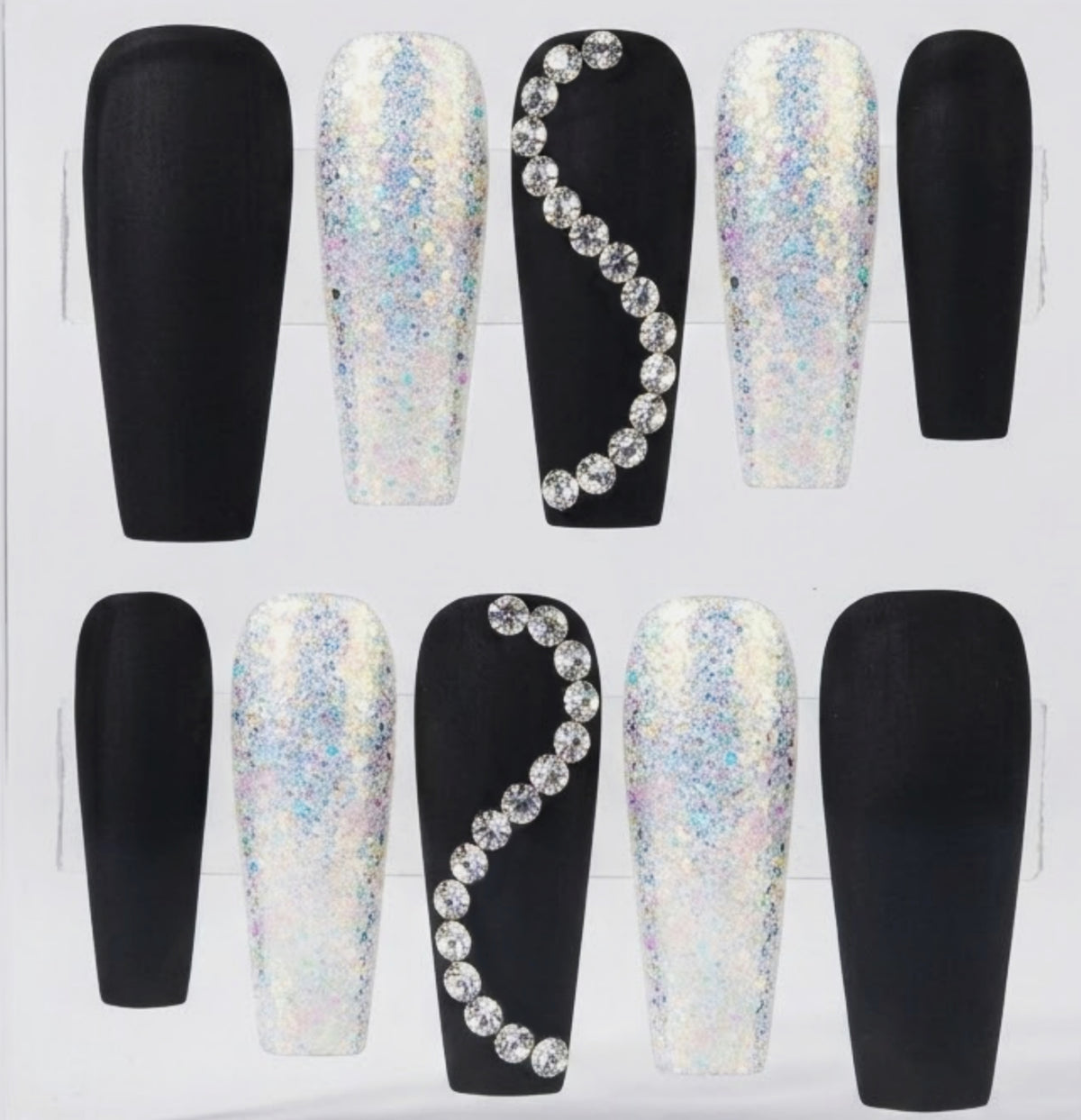 A set of coffin-shaped press-on nails displayed in a clear plastic tray, featuring matte black and white iridescent glitter designs with rhinestone accents.
