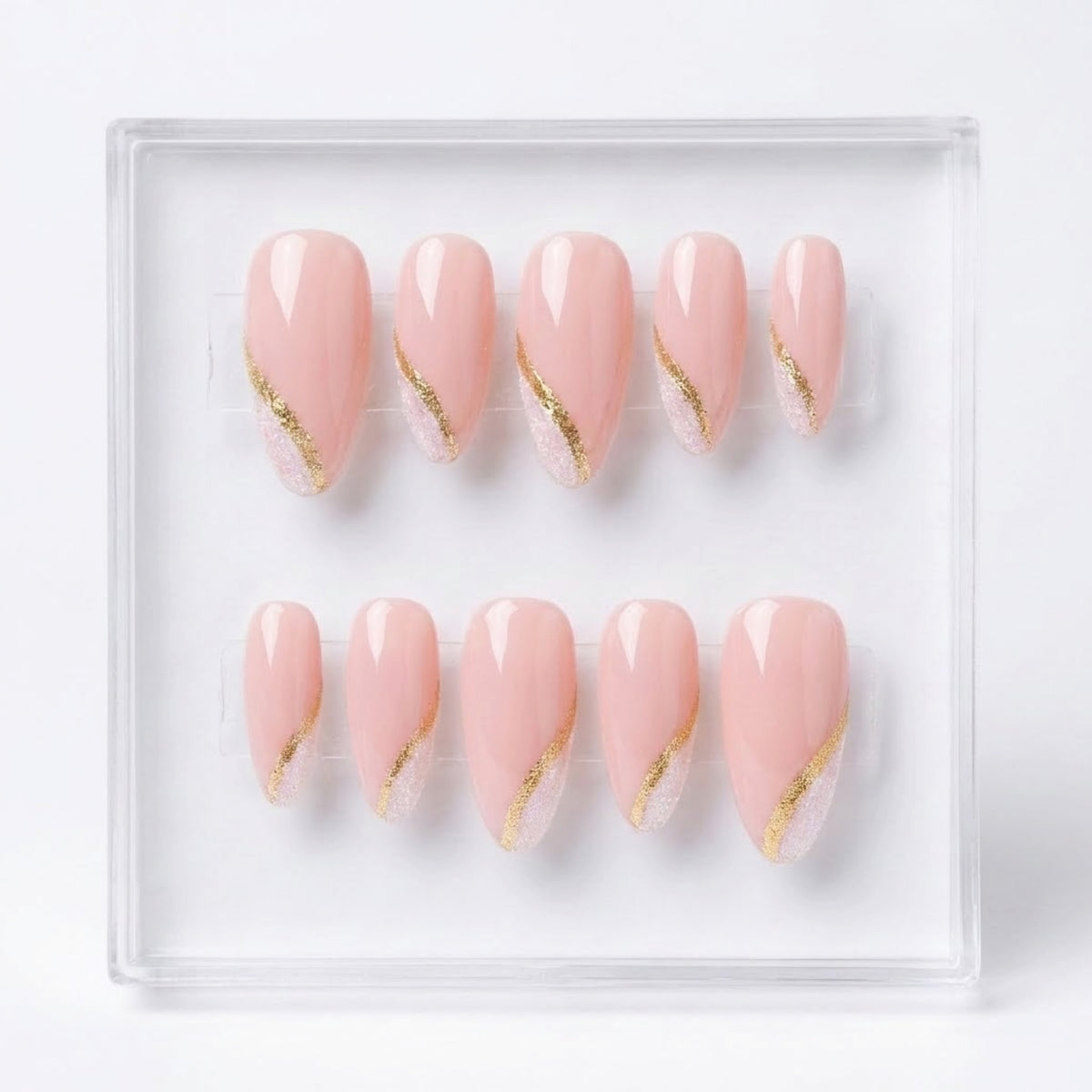 Ten-piece set of press-on nails in a clear plastic tray, featuring a glossy pale pink color with a diagonal gold glitter accent.