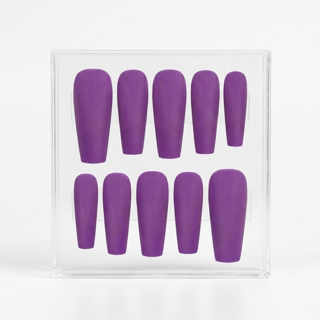 A set of ten matte purple press-on nails in various lengths, displayed inside a clear plastic square box against a white background.