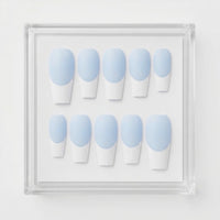 A set of ten coffin-shaped press-on nails with a light blue and white French tip design, displayed inside a clear acrylic square frame against a white background.