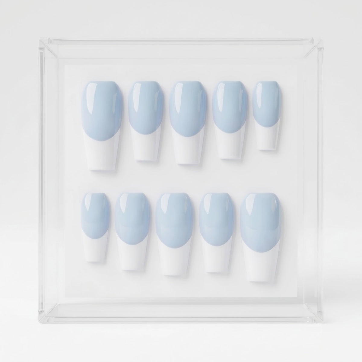 A set of ten press-on nails arranged in two rows inside a clear square display box. Each nail has a light blue base and white french tips.