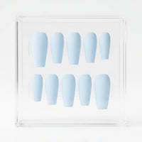 A set of ten light blue press-on nails arranged in two rows inside a clear acrylic display box on a white background.