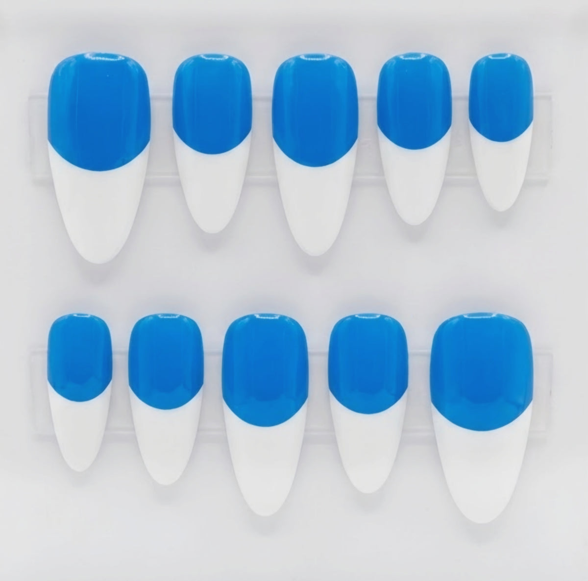 Ten false press-on nails arranged in two rows of five on a clear plastic display tray, featuring a two-tone design with a bright blue base and white french tips.