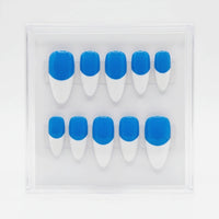 A set of ten false press-on nails arranged in two rows inside a clear plastic display case. Each nail has a bright blue base and white french tips.