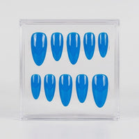 A set of ten glossy bright blue press-on nails arranged in two rows inside a clear plastic display box, photographed against a plain light gray background.
