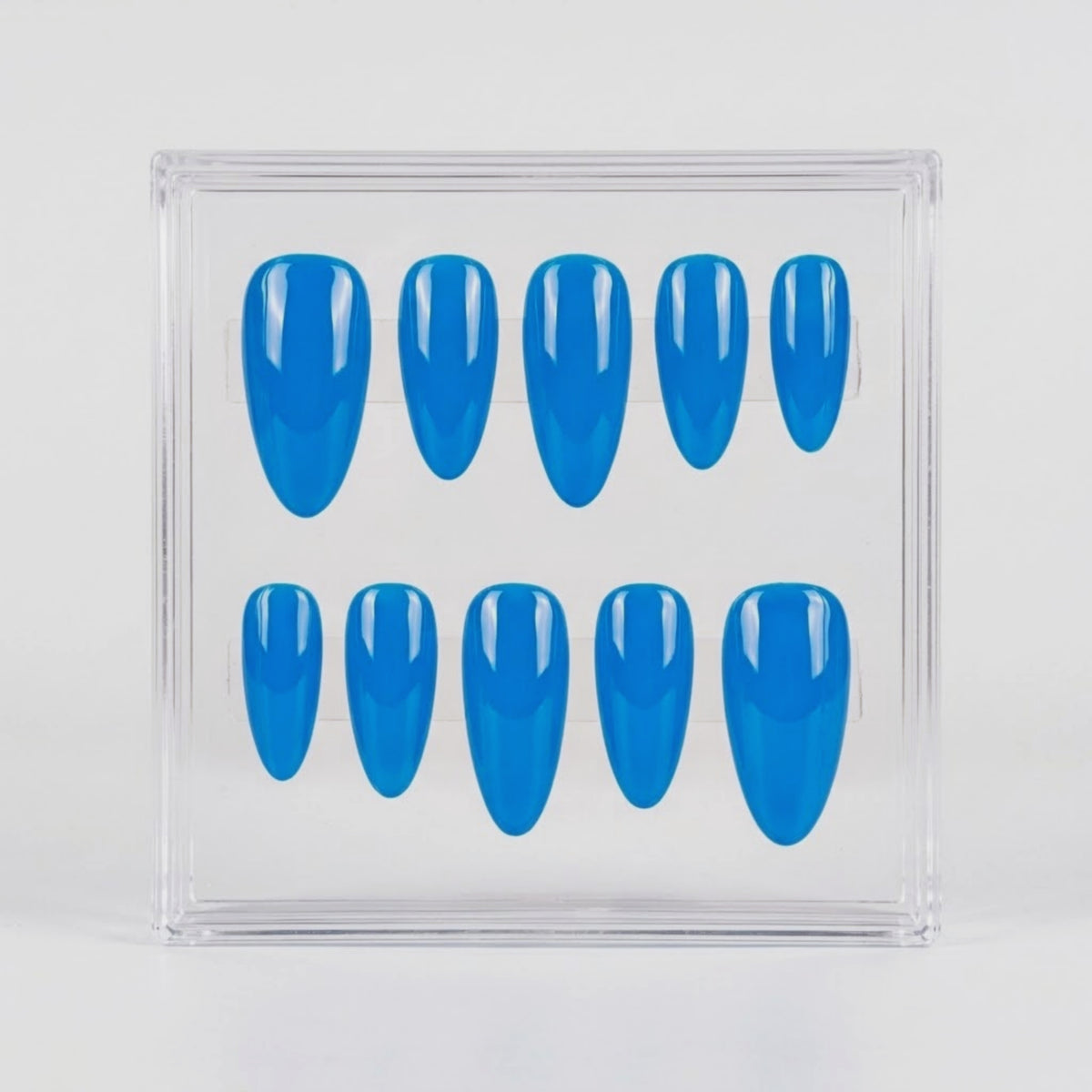 A set of ten glossy bright blue press-on nails arranged in two rows inside a clear plastic display box, photographed against a plain light gray background.
