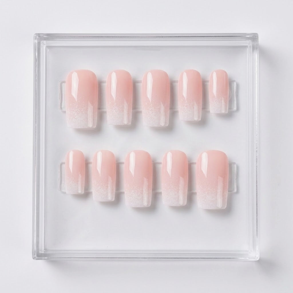 Ten square press-on nails with a soft pink ombre gradient transitioning to white at the tips, displayed in a clear acrylic tray on a white background.