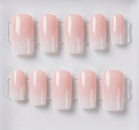 Ten square press-on nails with a glossy pale pink to white ombre gradient, arranged in two rows on a clear display card against a white background.