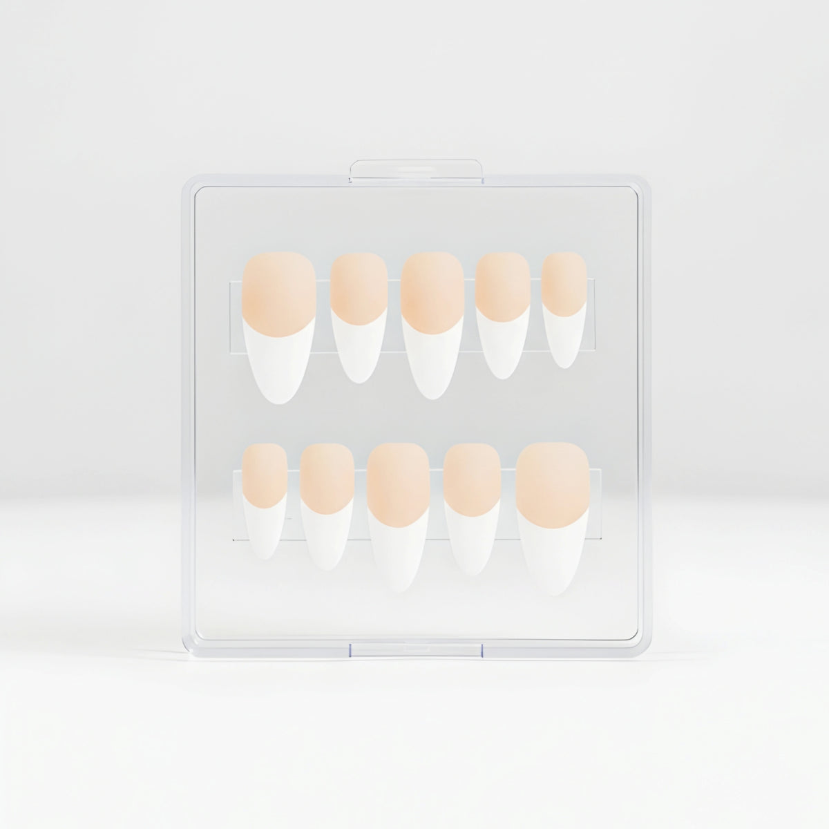A set of coffin press-on nails in a clear plastic case, featuring a matte french design with white tips and  a light peach nude bases.
