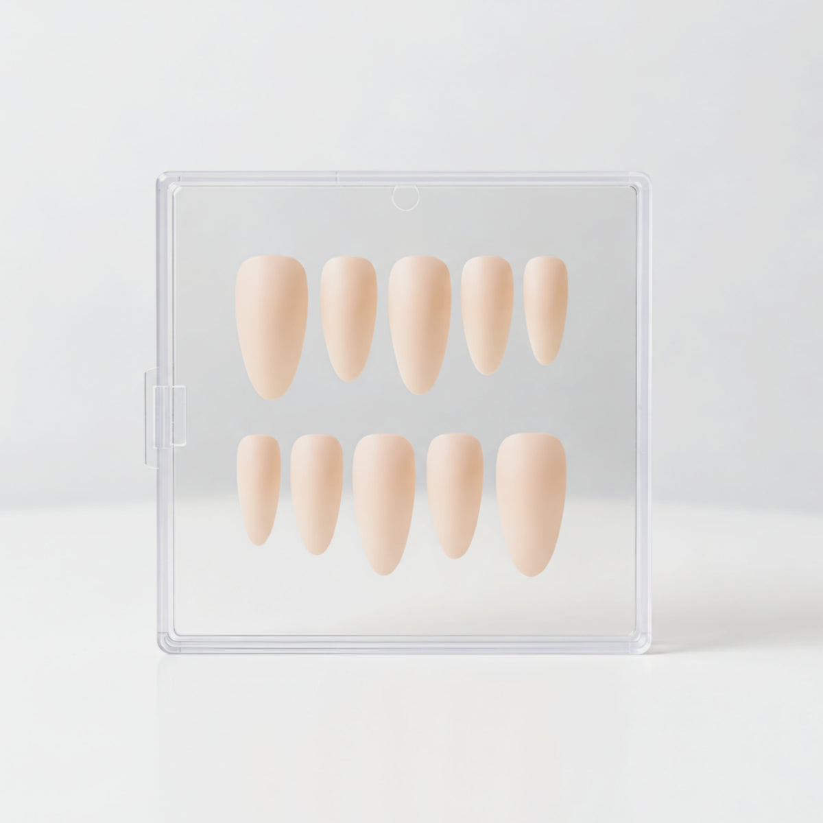 Ten almond beige nude matte press-on nails in a dual-row arrangement inside a clear plastic storage case, set against a seamless white background.