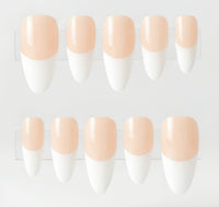 Ten false press-on nails arranged in two rows of five on clear plastic tape, featuring a glossy nude-peach base and white french tips.