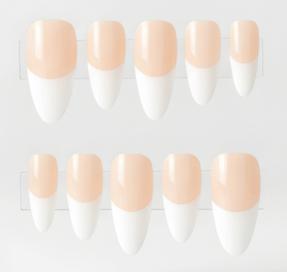 Ten false press-on nails arranged in two rows of five on clear plastic tape, featuring a glossy nude-peach base and white french tips.