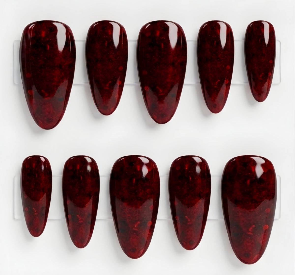 A set of ten glossy press-on nails with a deep red glitter pattern, displayed on a clear plastic hanger against a white background.