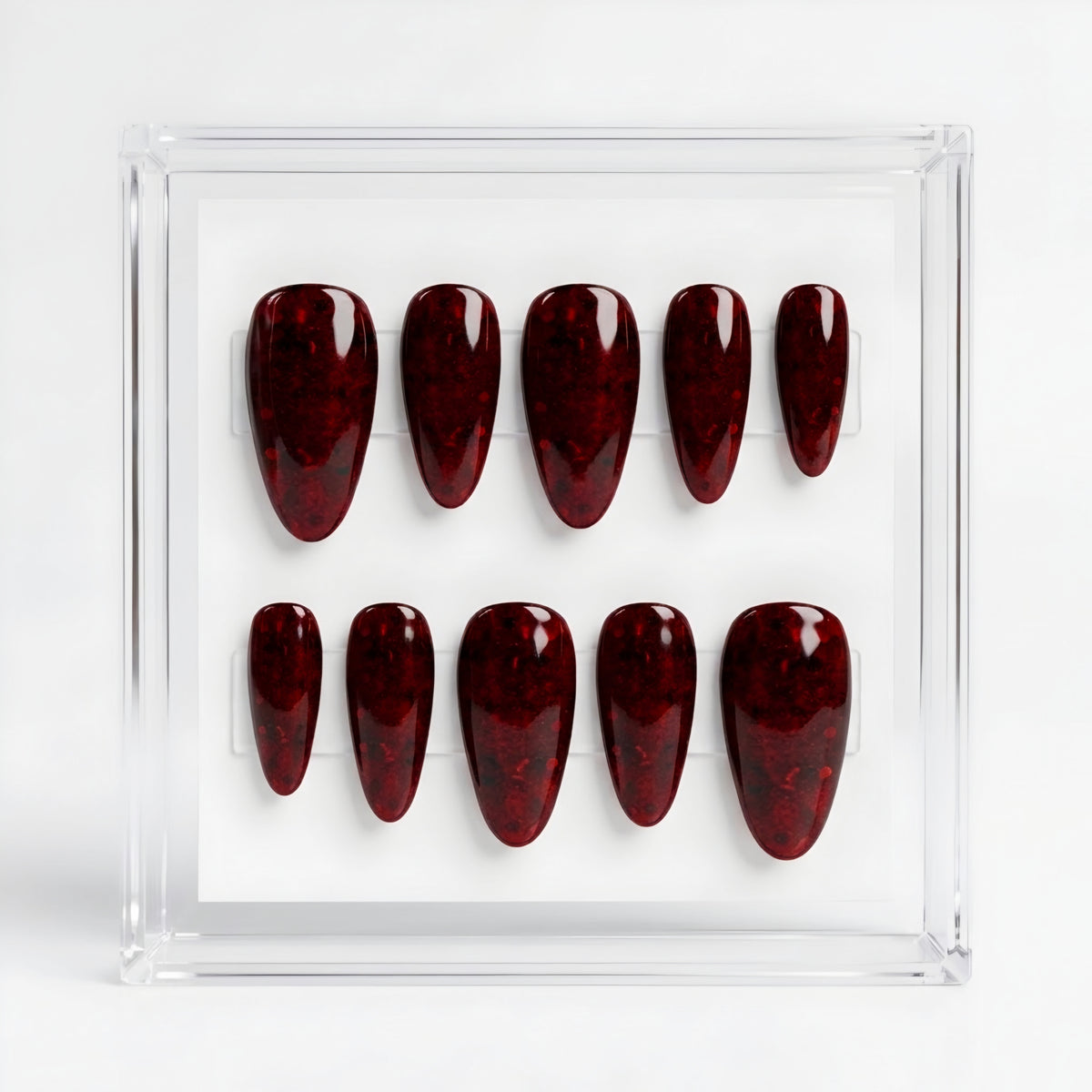 A set of ten glossy dark red glittery press on nails, displayed inside a clear acrylic case on a white background.