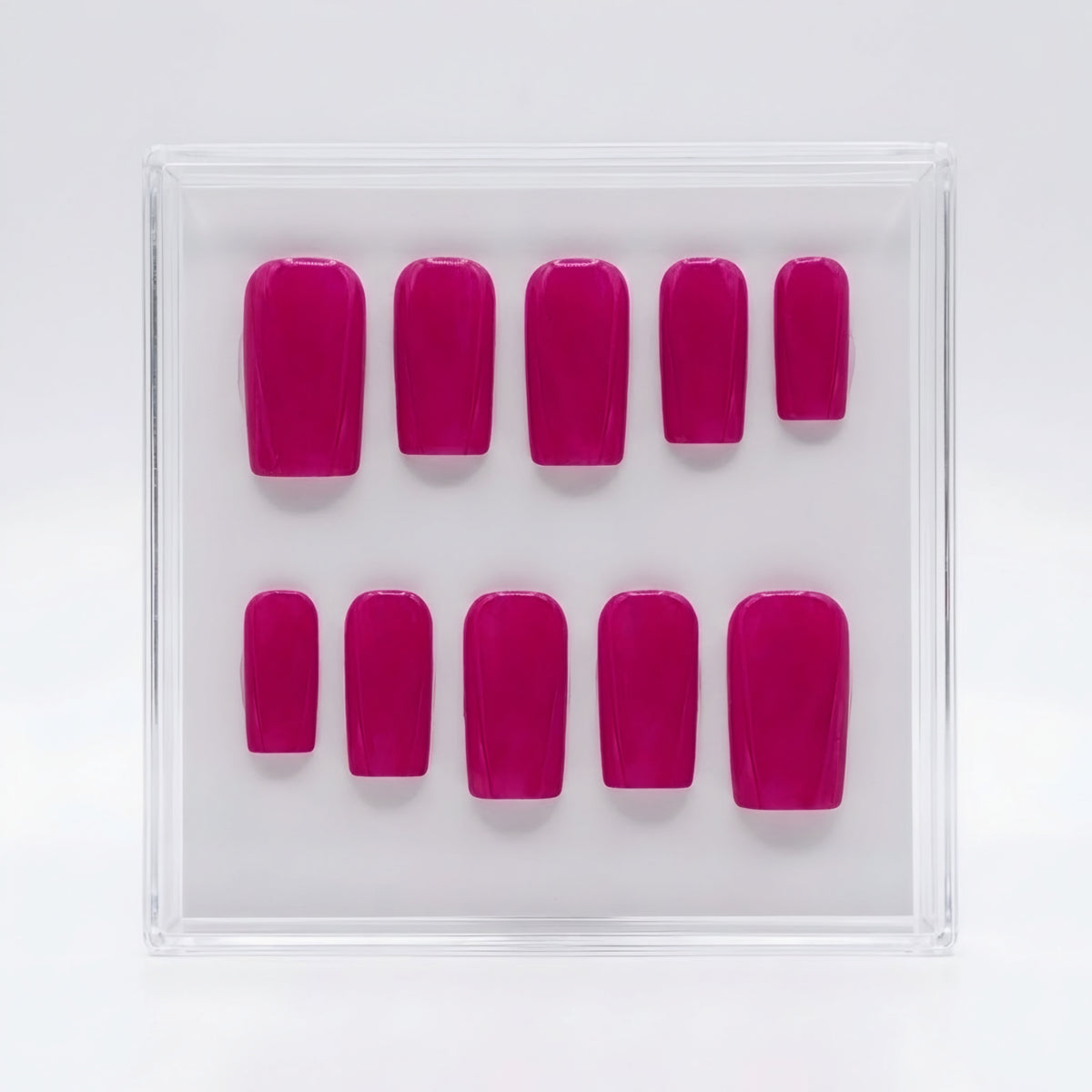A set of ten berry pink press-on nails arranged in two rows inside a clear plastic display box on a white background.