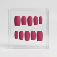 A set of ten false press-on nails in a dusty berry pink color, arranged inside a clear acrylic display box on a light gray background.