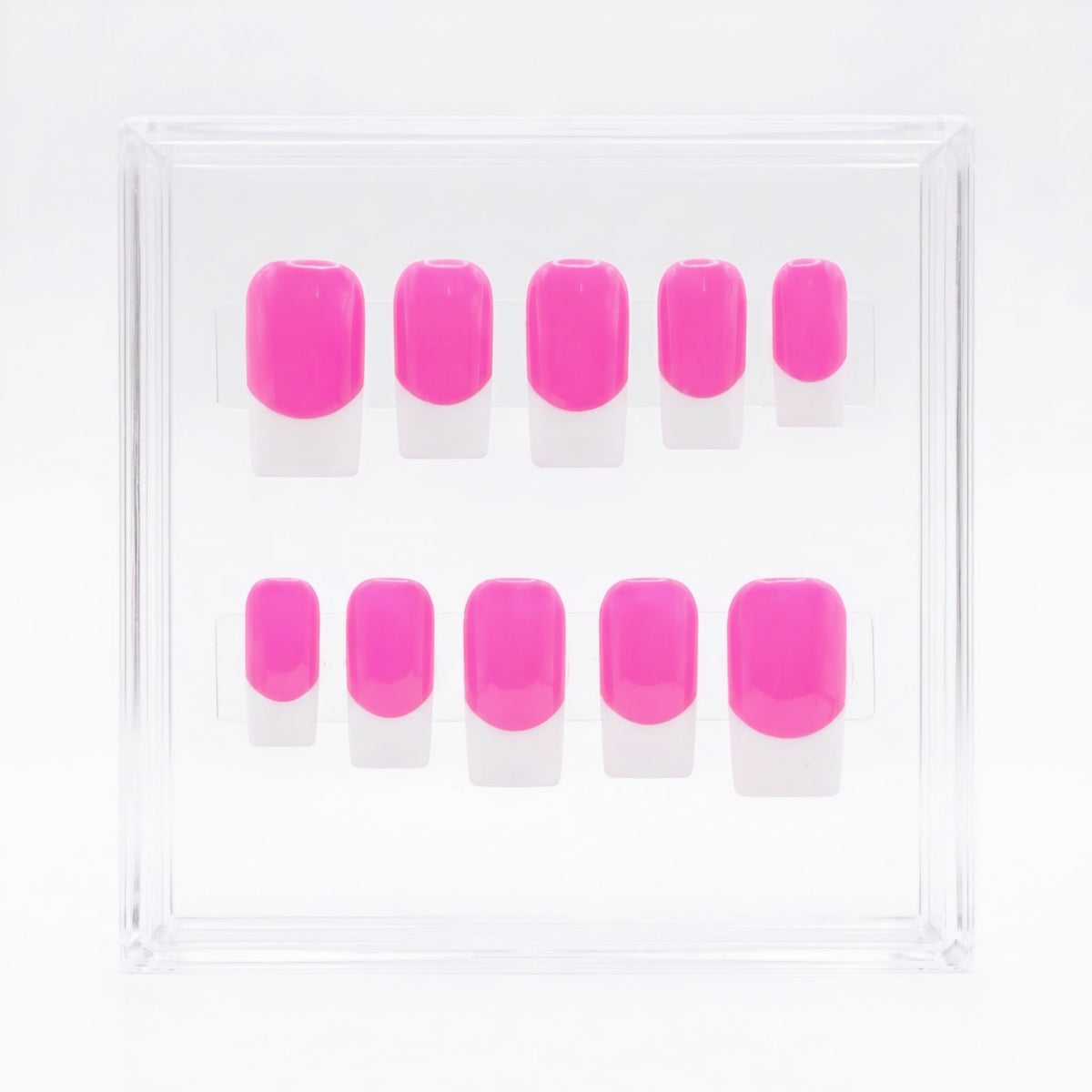 A set of ten bright pink press-on nails with white french tips, arranged in two rows inside a clear square plastic display box on a white background.
