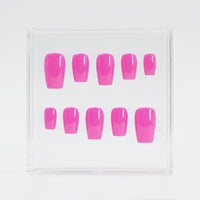 Ten bright pink press-on nails arranged in two rows inside a clear square plastic display box on a white background.