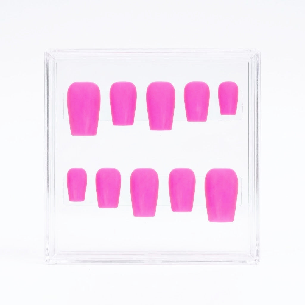 A set of ten bright pink press-on nails arranged inside a clear plastic display box on a white background.