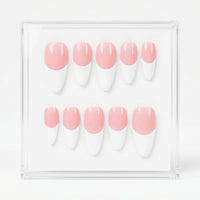 A set of ten press-on nails with a pink and white French tip design, displayed inside a clear acrylic case on a white background.