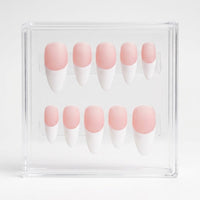 A set of ten press-on nails with a matte pink and white French tip design, displayed inside a clear acrylic case on a white background.