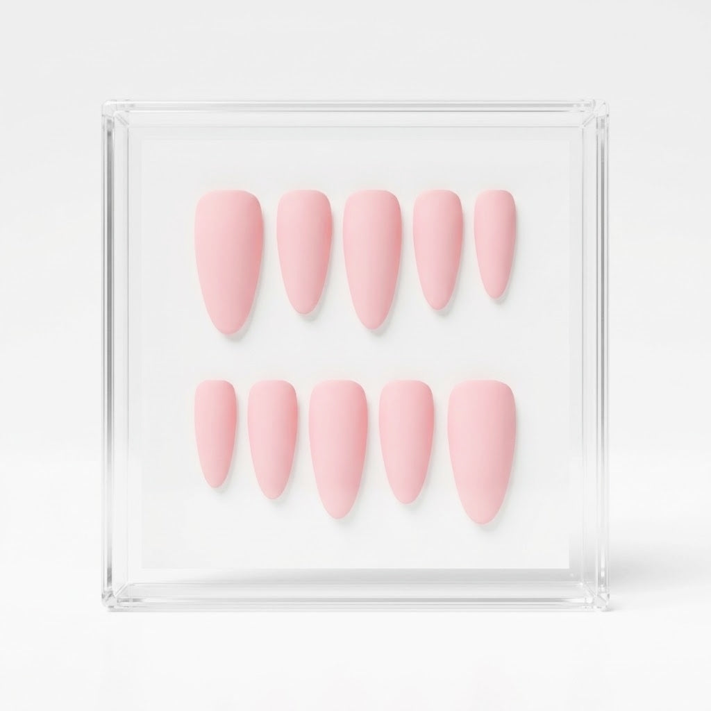 Ten light pink press-on nails arranged in two rows inside a clear acrylic display box on a white background.