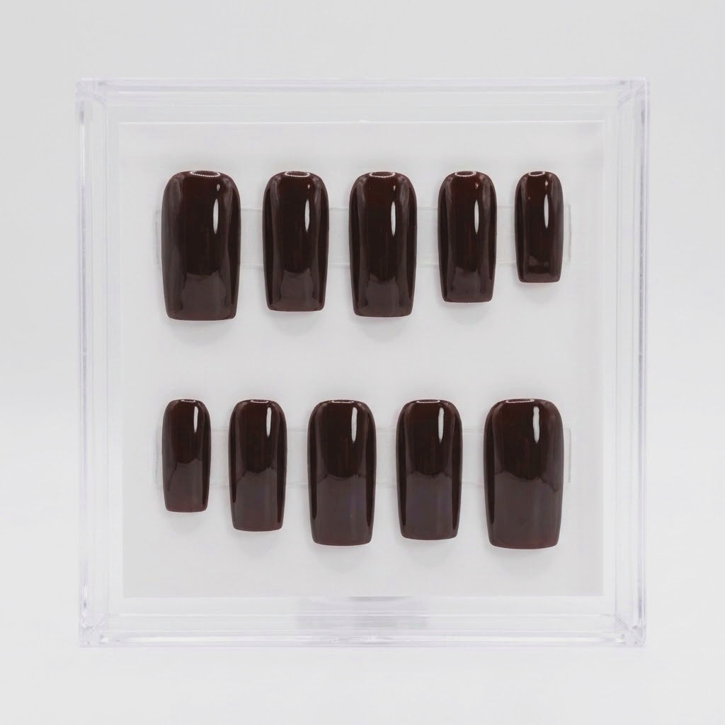 A set of glossy dark brown press-on nails arranged in two rows inside a clear square display box on a white background.