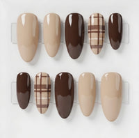Ten press-on nails displayed against a light gray background. The set includes nude beige and dark brown solid colors, as well as two plaid designs in beige and brown.