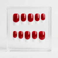 A set of ten false press-on nails with a glossy red and white French tip design, displayed inside a clear acrylic case on a light gray background.