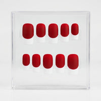 A set of ten matte press-on nails with a bright red base and a white french tip, displayed inside a clear acrylic case on a white background
