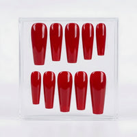 Ten coffin shaped bright red press on nails in a glossy finish, in a clear case on a white backgroung.