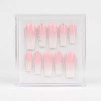 A set of 10 coffin-shaped press-on nails with a pink-to-white ombre gradient, displayed inside a clear acrylic case on a white background.