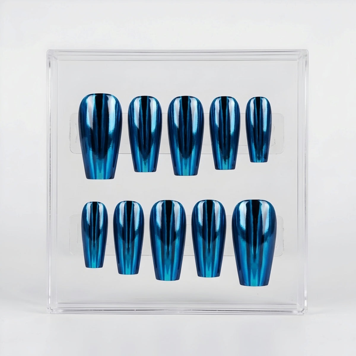 A set of ten coffin-shaped press-on nails with a metallic blue chrome finish, displayed inside a clear acrylic case on a white background.