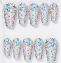 Ten false press-on nails arranged in two rows of five on a clear display stand, featuring a dense glitter finish with iridescent blue, purple, and gold flakes over a white base.