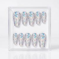 A set of ten press-on nails in a clear square display case, featuring chunky silver iridescent glitter.