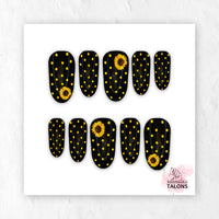 Black and yellow press-on nails with polka dots and sunflower nail art in medium oval shape.
