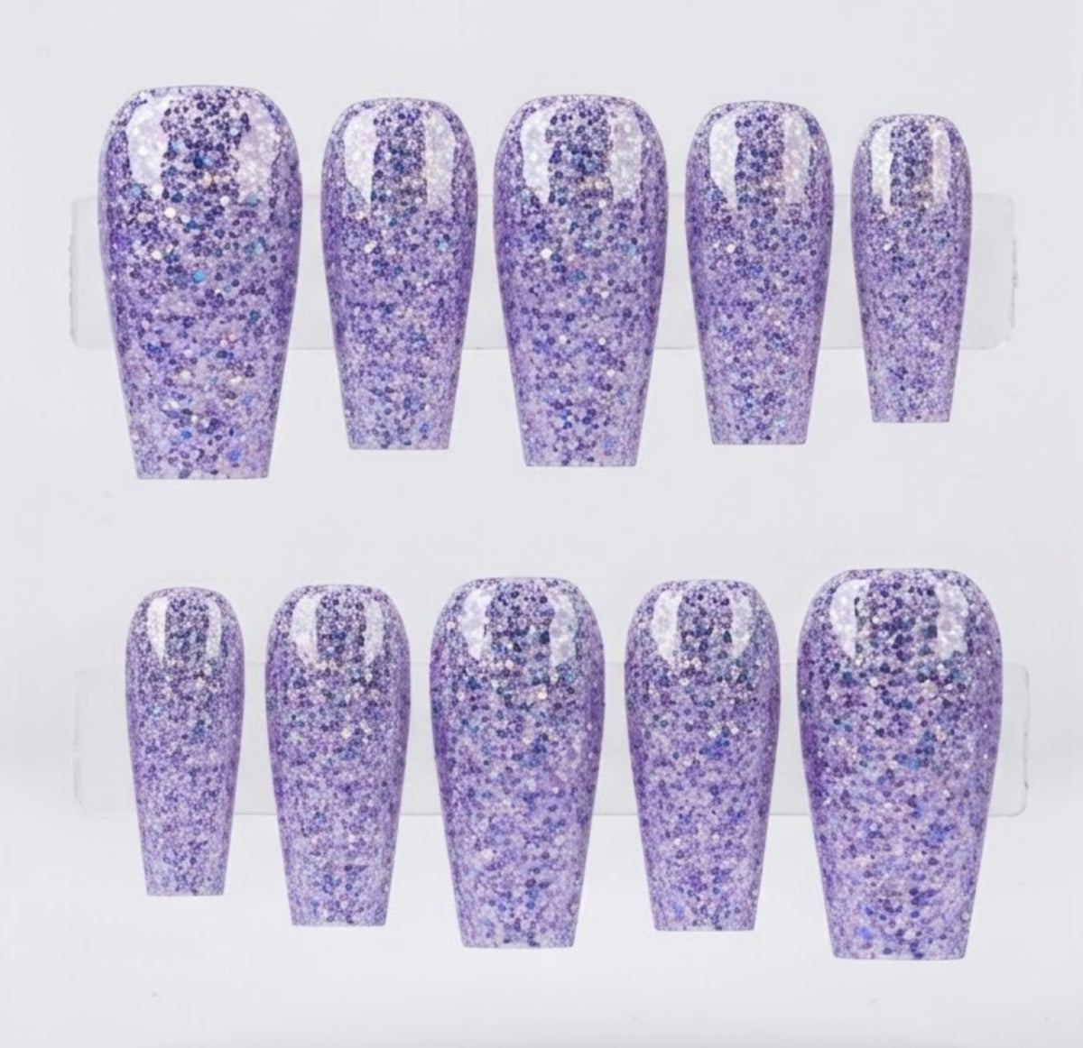 Ten press-on nails with a glittery lavender purple finish, arranged in two rows of five on a clear display stand against a white background.