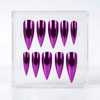 Ten metallic purple stiletto false nails arranged in two rows inside a clear acrylic display box on a white background.