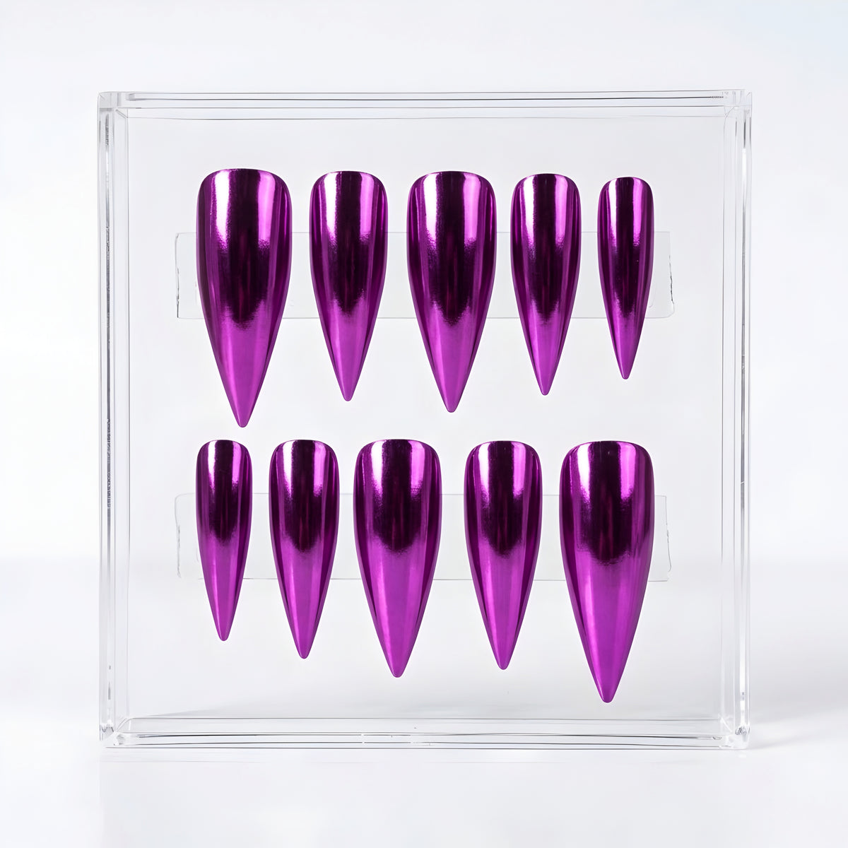 Ten metallic purple stiletto false nails arranged in two rows inside a clear acrylic display box on a white background.