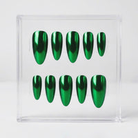 Ten metallic emerald chrome green press-on nails arranged in two rows inside a clear acrylic display box on a light gray background.