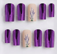 A set of square press-on nails displayed on a clear plastic tray against a white background. The set features five nails with a metallic purple reflective finish and three nude beige nails decorated with a purple lavender floral design.