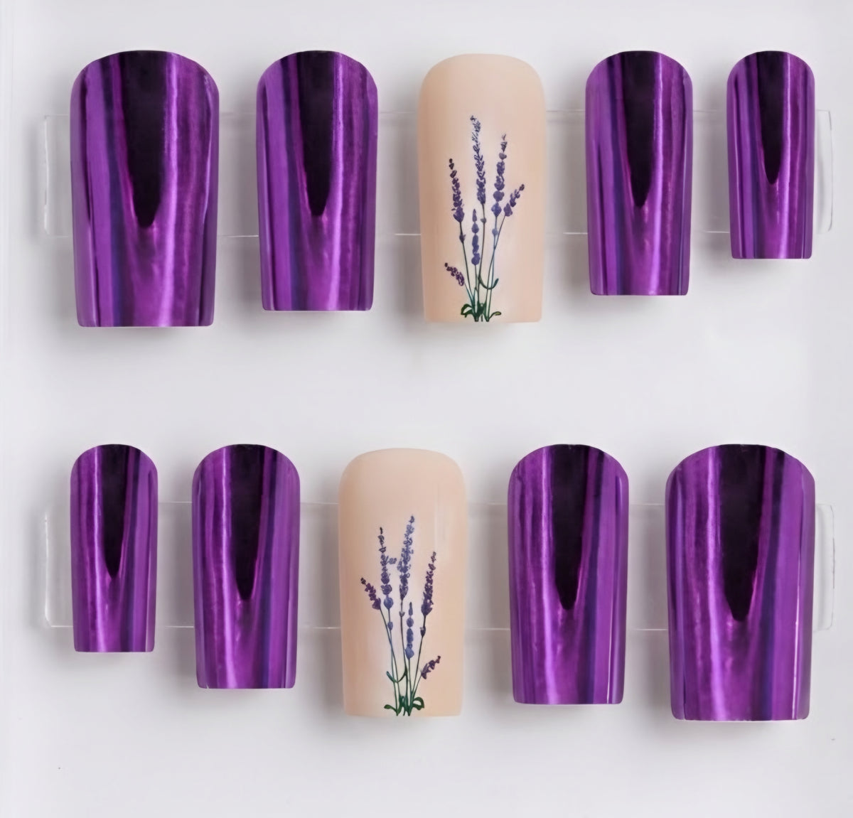 A set of square press-on nails displayed on a clear plastic tray against a white background. The set features five nails with a metallic purple reflective finish and three nude beige nails decorated with a purple lavender floral design.