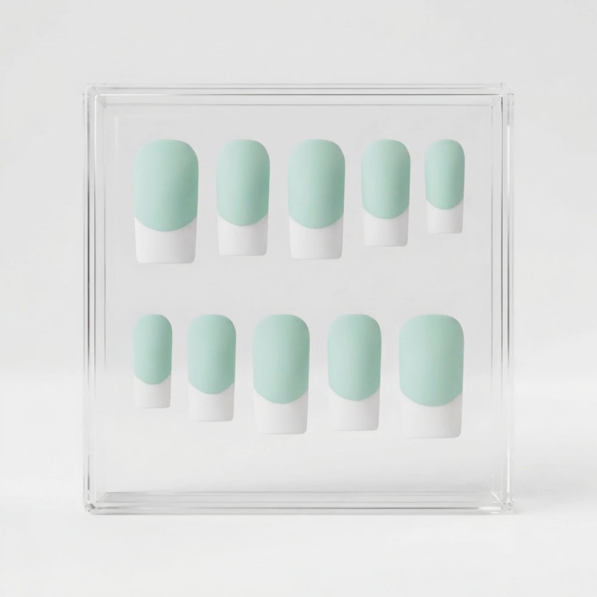 A set of ten press-on nails displayed in a clear acrylic box, featuring a mint green and white French tip design.