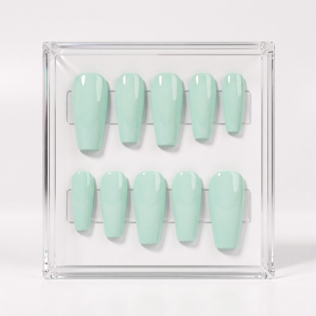A set of ten glossy press-on nails in a pale mint green color, displayed inside a clear acrylic square tray on a white background.
