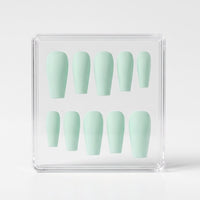 A set of ten pastel mint green press-on nails arranged inside a clear acrylic display box on a light gray background.
