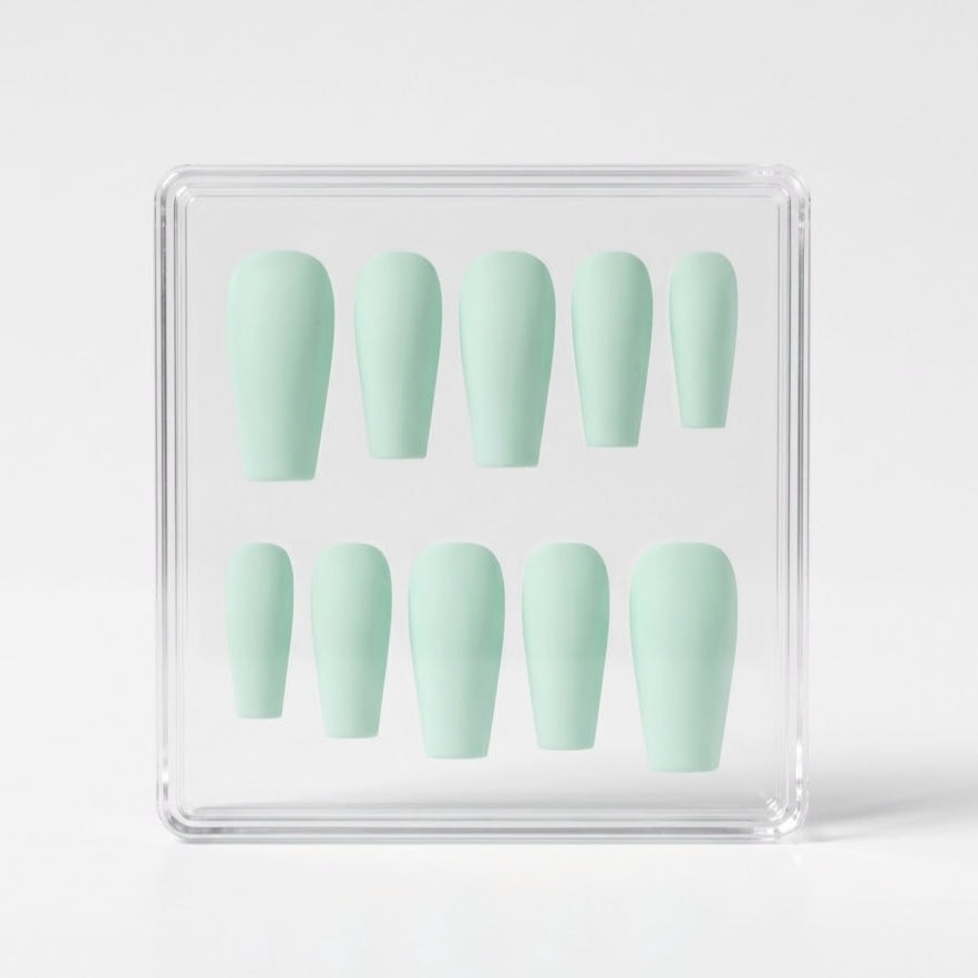 A set of ten pastel mint green press-on nails arranged inside a clear acrylic display box on a light gray background.