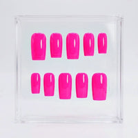 Ten neon hot pink press-on nails arranged in two rows inside a clear square plastic display box on a white background.