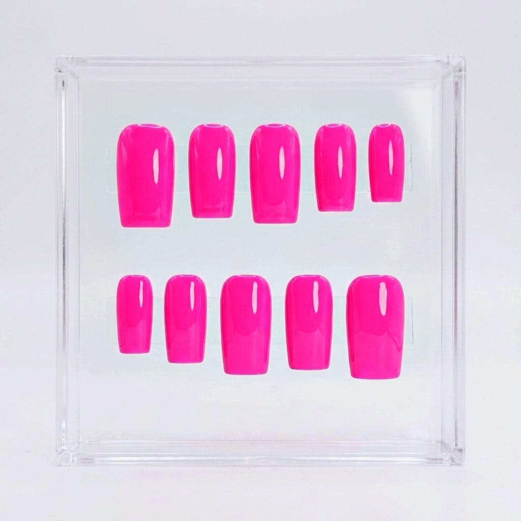 Ten neon hot pink press-on nails arranged in two rows inside a clear square plastic display box on a white background.