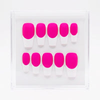 A set of press-on nails in a clear plastic display case, featuring a bold neon pink base and white french tips, arranged in two rows of five.