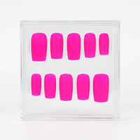 A set of ten neon hot pink press-on nails arranged in two rows inside a clear plastic display box, photographed against a clean white background.